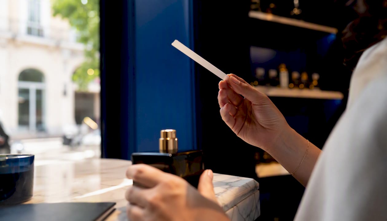 Dans une parfumerie raffinée, des mains appliquent délicatement quelques gouttes de fragrance sur la peau pour en découvrir toutes les subtilités.