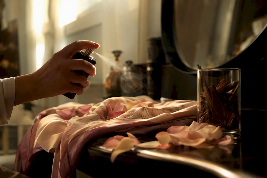 Pulvérisation manuelle du parfum oud rose sur une écharpe en soie